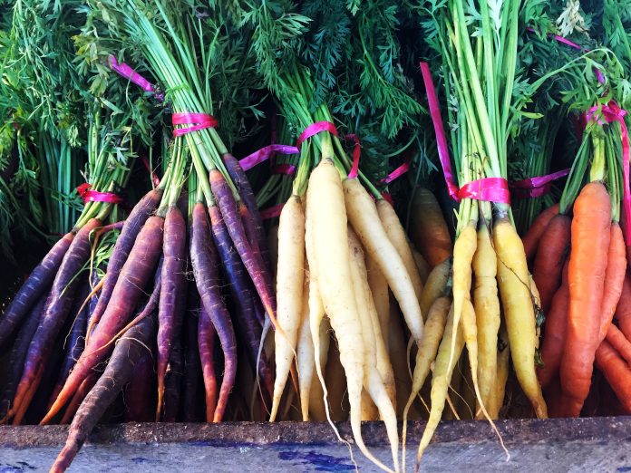 A variety of colourful heritage carrots on an outdoor market stall