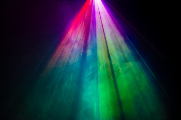 bellissimo proiettore a lente larga di colore dell'arcobaleno con fascio di luce per il film e il cinema di notte. riflettore di struttura del fumo. proiezione per multimedia. sfondo nero.