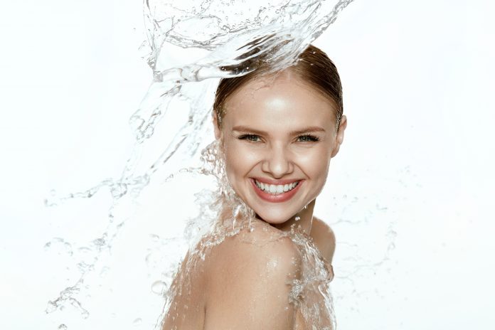 Beauty. Woman With Water On Face And Body. Spa Skin Care. Beautiful Smiling Girl Model With Water Splashes On White Background. High Resolution