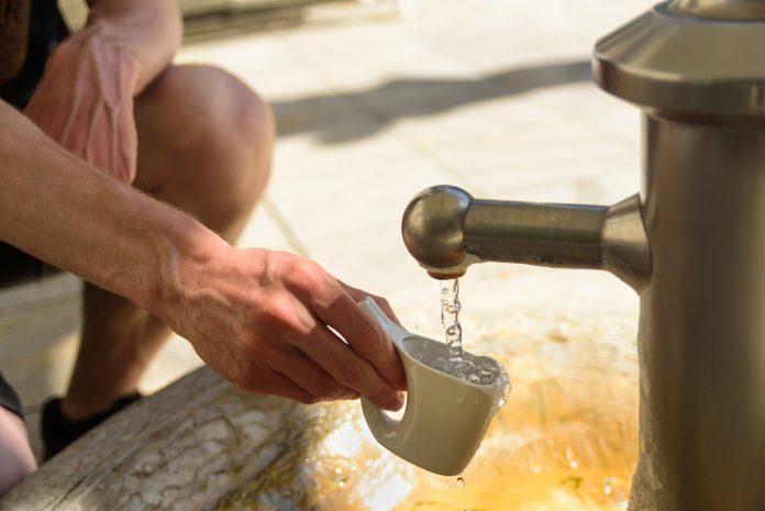Man catching a water from hot mineral spring in Karlovy Vary in special mug