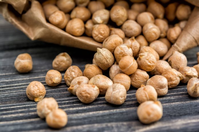 Raw chickpeas in paper bag on wooden background. Healthy food