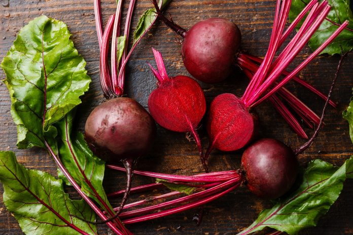 Red Beetroot with herbage green leaves on wooden background