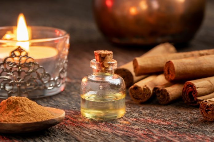 A bottle of essential oil with true cinnamon sticks and powder