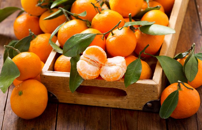 Fresh mandarin oranges fruit or tangerines with leaves in the wooden box