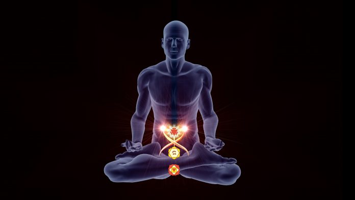 Silhouette in an enlightened Yoga meditation pose with three highlighted Hindu Chakras.