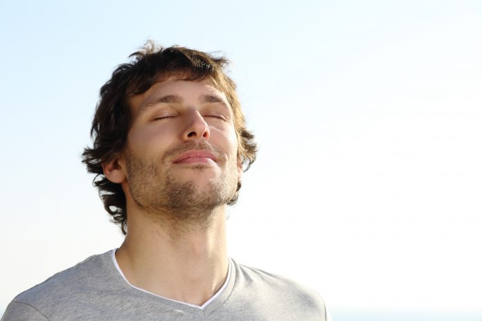 Attractive man breathing outdoor with the sky in the background
