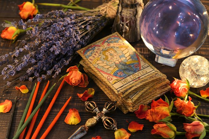 Tarot cards with magic crystal ball, candles and lavender flowers. Wicca, esoteric, divination and occult background with vintage magic objects for mystic rituals