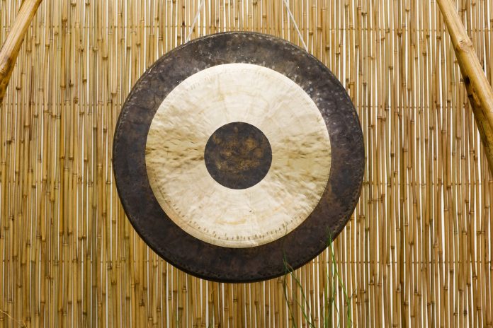 "Traditional oriental gong on bamboo mat, front view"