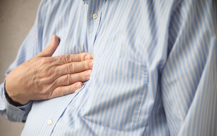 businessman indicates where he feels discomfort from heartburn