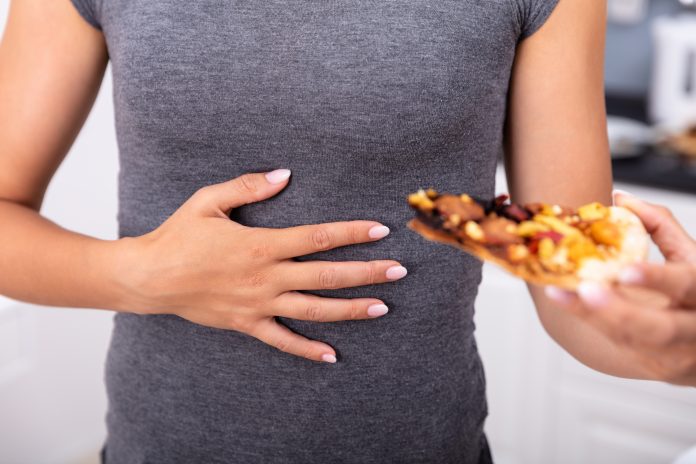 Close-up Of A Woman Holds A Slice Of Pizza And Rubs His Belly