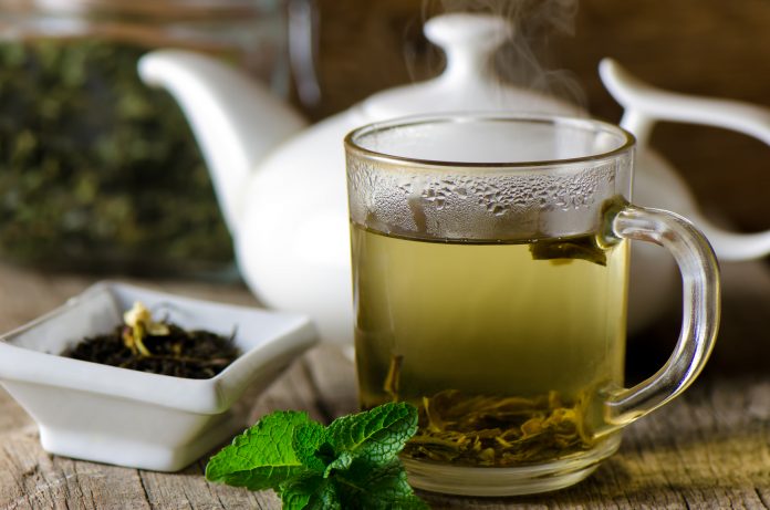 Tasse en verre avec du thé vert frais et de la menthe.
