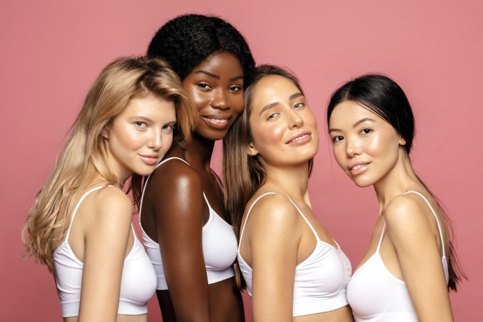 Multi racial Ethnic Group of Womans with diffrent types of skin standing together and looking on camera. Diverse ethnicity women - Caucasian, African and Asian against pink background