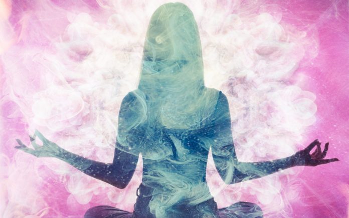 Práctica espiritual. Equilibrio de la armonía. Silueta de mujer meditando en una doble exposición de humo etéreo rosa.