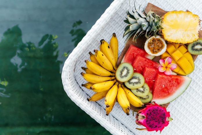 Still life image of tropical fruits and flowers near the pool: water melon, mango, mangosteen, passion fruit