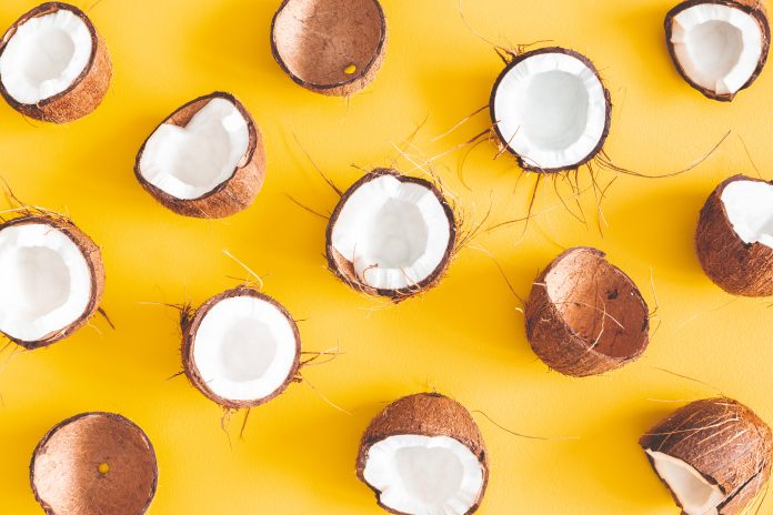 Kesän koostumus. Kookospähkinäkuvio keltaisella taustalla. Kesä käsite. Flat lay, ylhäältä katsottuna