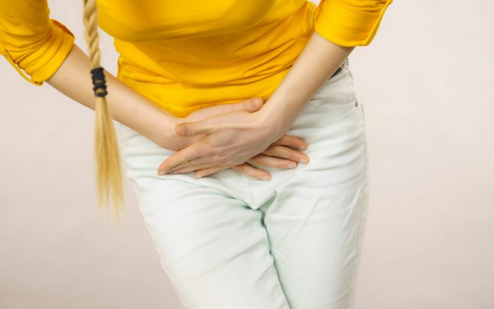 Closeup young sick woman with hands holding pressing her crotch lower abdomen. Medical or gynecological problems, healthcare concept