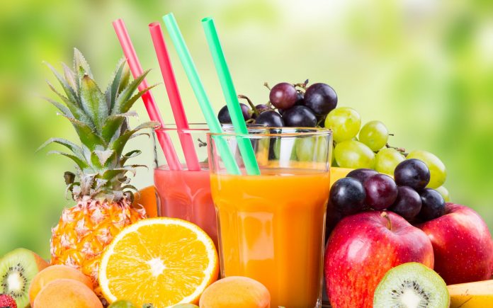 Färsk juice med frukter på träbord med natur grön bakgrund