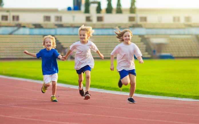 Child running in stadium. Kids run on outdoor track. Healthy sport activity for children. Little girl at athletics competition race. Young athlete in training. Runner exercising. Jogging for kid.