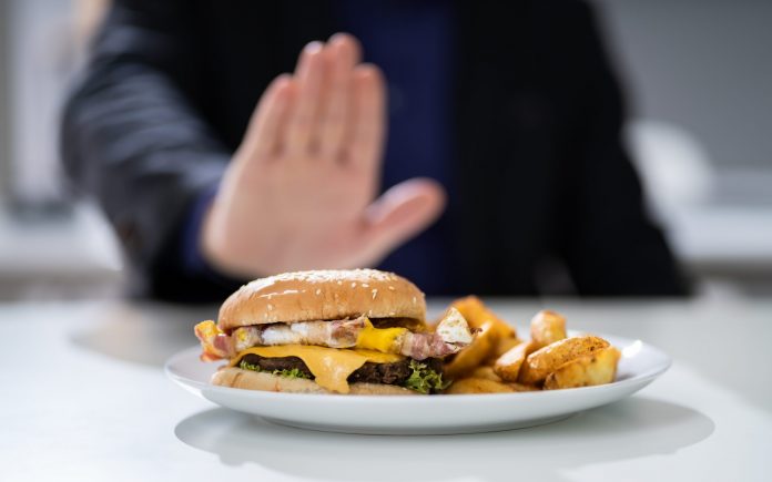 Primo piano della mano di un uomo che si rifiuta di mangiare l'hamburger di Fest Food