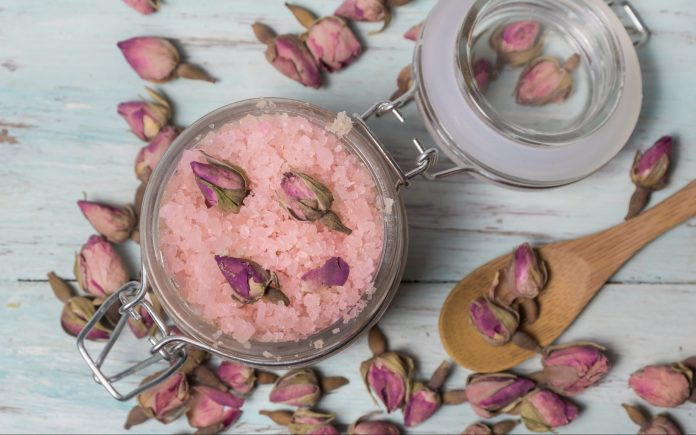 Homemade spa of rose bath salts on a light wooden background. Cosmetics and natural medicine