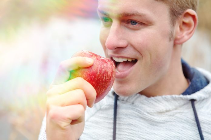 portrait of handsome man eating an red apple