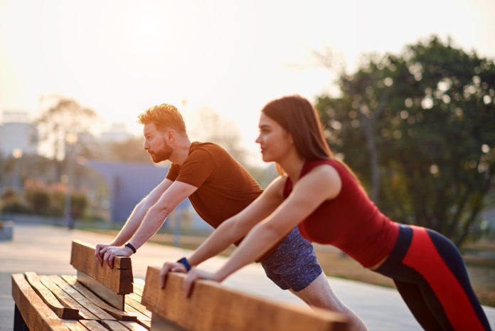 Urheilullinen pariskunta harrastaa liikuntaa kaupunkialueella auringonlaskun / auringonnousun aikana.