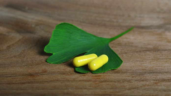 Ginkgo Biloba Blätter mit Tabletten auf Holztisch